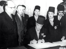 Tahar Ben Ammar, président du Conseil tunisien, signe le protocole de l’Indépendance. À g., Christian Pineau, ministre français des Affaires étrangères. À dr., Mongi Slim, ministre de l’Intérieur tunisien, et Ahmed Mestiri, chef de cabinet de Mongi Slim. Au Quai d’Orsay, à Paris, le 20 mars 1956. © Archives J.A.