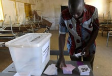 Un homme s’empare des bulletins de vote lors du référendum sur les réformes constitutionnelles à Fatick au Sénégal le 20 mars 2016. © Seyllou/AFP