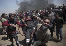 Des manifestants palestiniens transportent un homme blessé par les troupes israéliennes lors d’une manifestation meurtrière à la frontière de la bande de Gaza avec Israël, à l’est de Khan Younis, dans la bande de Gaza, lundi 14 mai 2018. © Khalil Hamra/AP/SIPA