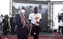 Le président sénégalais Macky Sall (masqué) après le retour au Sénégal de l’équipee nationale, victorieuse lors de la Coupe d’Afrique des nations. À ses côtés, le capitale des Lions de la Teranga, Kalidou Koubaly, tient le trophée. © SEYLLOU/AFP.