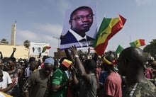 Des manifestants tiennent un drapeau du Sénégal et un portrait de l’opposant et maire de Ziguinchor, Ousmane Sonko, à Dakar, le 8 juin 2022. © SEYLLOU/AFP.