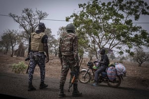 Un soldat et un officier du Bénin arrêtent un motard à un checkpoint, à Porga, dans le nord du pays, en mars 2022. © Marco Simoncelli/AP/SIPA.