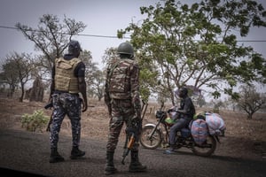 Un policier et un soldat béninois arrêtent un motocycliste à un poste de contrôle à l’extérieur de Porga, au Bénin, le 26 mars 2022. © Marco Simoncelli/AP/SIPA