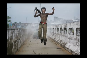 Un militaire libérien exulte après un tir de roquettes sur des forces rebelles, à Monrovia, le 20 juillet 2003. © Chris Hondros/Getty Images via AFP.