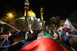 Des manifestants brandissant des drapeaux iraniens et palestiniens se sont rassemblés place de Palestine, à Téhéran, le 14 avril 2024, après que l’Iran a lancé son offensive contre Israël. © ATTA KENARE / AFP