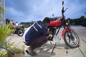 Employé de ZedMotors insérant une batterie dans une moto électrique, à Cotonou, le 21 octobre 2022. © Yanick Folly / AFP