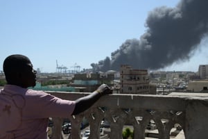 Un habitant regarde un nuage de fumée après une attaque de drone sur le port de Port Soudan, le 6 mai 2025. © AFP