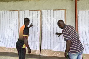 Des hommes cherchent leurs noms sur les listes électorales après que la Commission électorale indépendante de Côte d’Ivoire a affiché la liste provisoire, à Abidjan, le 18 mars 2025. © Sia Kambou / AFP