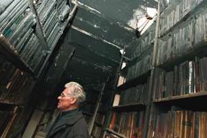Le père Jean Fontaine au milieu des décombres calcinés de la réserve de livres © Ons Abid pour J.A