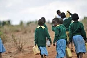 Des élèves kenyans transportent de l’eau dans des bidons pour aller à l’école le 17 août 2009. © AFP