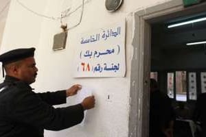 Un policier égyptien pose une affiche devant un bureau de vote à Alexandrie, le 28 novembre. © AFP