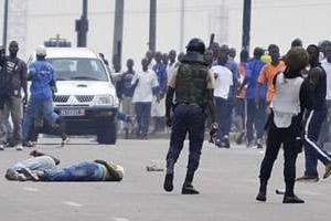 Deux blessés à terre à Abidjan, le 16 décembre, après la dispersion d’un rassemblement. © AFP