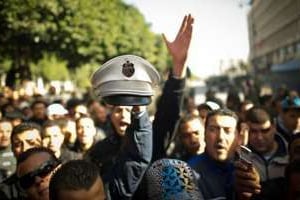 Un manifestant brandit la casquette d’un policier à Tunis le 22 janvier. © AFP