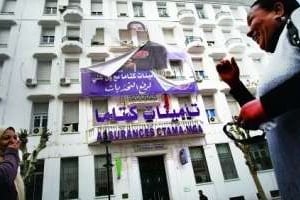 Des Tunisoises devant une affiche en lambeaux de Ben Ali, à Tunis, le 16 janvier. © Christophe Ena / AP / Sipa