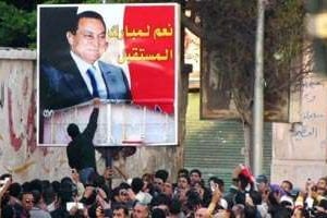 Des manifestants déchirent un poster du président Moubarak dans la ville d’Alexandrie. © AFP