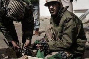 Des combattants libyens anti-gouvernementaux préparent leurs ceintures cartouchières à Ajdabiya. © AFP