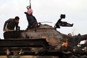 Des insurgés libyens sont rassemblés autour d’un tank des forces pro-kaddafi en train de brûler. © AFP