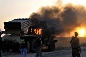 Des rebelles libyens près d’un lance-roquette incendié à Ras Lanouf, le 27 mars. © AFP