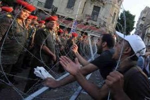 Soldats égyptiens et manifestants se font face à travers des barbelés au Caire le 23 juillet 2011 © AFP