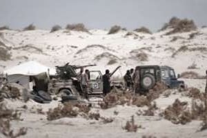 Des combattants rebelles libyens entre les dunes de sable, aux abords de la ville de Brega, le 10 ao © AFP