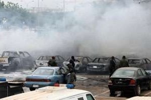De la fumée au-dessus de véhicules endommagés par l’explosion d’une bombe, le 16 juin 2011. © Sunday Aghaeze/AFP