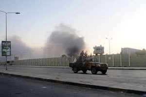 Des rebelles libyens passent devant le QG de Kadhafi à Tripoli, le 25 août 2011. © Filippo Monteforte/AFP