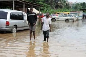 Deux hommes sur une route inondée à Lagos le 11 juillet 2011. © AFP