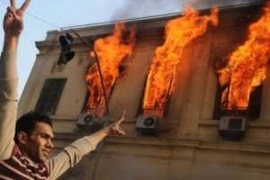 Un manifestant dans les rues du Caire près d’un bâtiment en flammes le 17 décembre 2011. © AFP