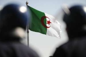 Deux policiers se tiennent devant le drapeau algérien. © AFP