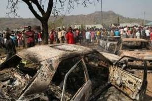 Voitures incendiées près de l’église Ste Theresa visée par un attentat, le 25 décembre 2011. © AFP
