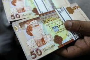 Des dinars libyens montrant le colonel Mouammar Kaddafi. © Patrick Baz/AFP