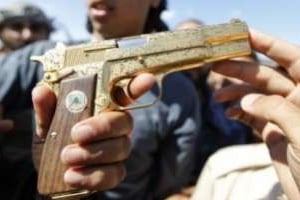 Le 20 octobre 2011 près de Syrte, un jeune rebelle exhibe le Parabellum 9 mm plaqué or de Kaddafi. © Thaier al-Soudan/Reuters