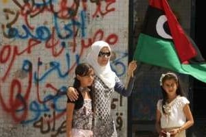Une femme, accompagnée de ses filles, agite le drapeau des rebelles libyens du CNT. © AFP
