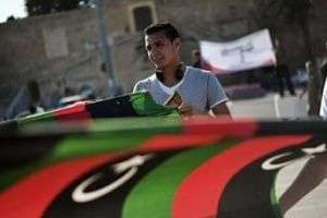 Un jeune homme devant le drapeau libyen pendant une manifestation, à Tripoli. © AFP