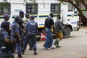 Des mineurs de Marikana accusés d’actes de violence sont escortés par des policiers. © AFP