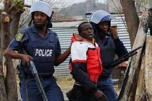 Des policiers sud-africains arrêtent un mineur à Marikana, le 15 septembre 2012. © AFP