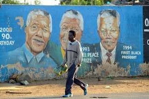 Un habitant de Soweto passe devant des peintures murales représentant l’ancien président. © AFP