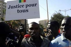 Un Sénégalais tenant une pancarte lors des manifestations le 19 mars 2011. © Erick Christian Ahounou/AFP