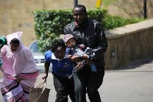 Un policier escorte des personnes qui quittent un centre commercial de Nairobi. © AFP