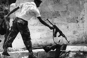Un milicien du front patriotique de Taylor abat un homme dans la rue en 1997 à Morovia. © Corinne Dufka/Reuters