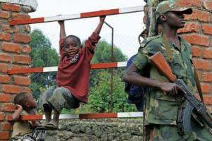 Des enfants jouent près d’un soldat rebelle du M23 le 7 mars 2013 à Bunagana. © AFP