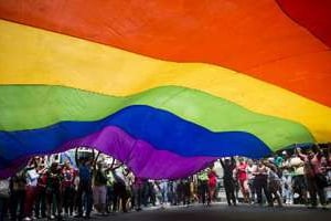 Des gens portent un drapeau arc-en-ciel lors de la Gay pride à Caracas, le 30 juin 2013. © AFP