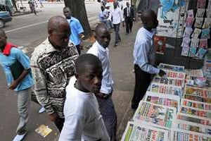 Des Ivoiriens devant un kiosque à Abidjan. © AFP