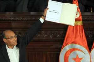 Le président tunisien Moncef Marzouki brandit un exemplaire signé de la nouvelle Constitution. © AFP