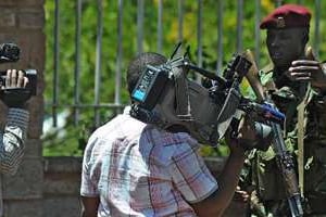 Un paramilitaire kényan demande à un journaliste de s’éloigner de l’entrée du stade Kasarani. © AFP