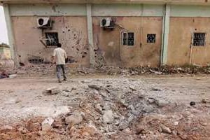 Un journaliste regarde le bâtiment endommagé d’un camp d’une brigade islamiste. © AFP