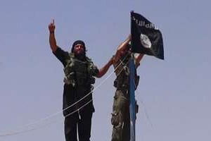 Des combattants de l’EIIL hissent le drapeau près de la frontière Syrienne, le 11 juin 2014. © AFP