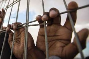 Des mains derrière un grillage dans un centre de détention. © AFP