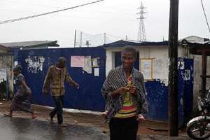 Des passants devant l’école qui sert de centre d’isolement des malades d’Ebola. © AFP