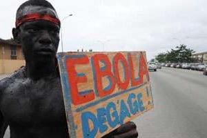 Un homme tient une pancarte Ebola dégage. © AFP